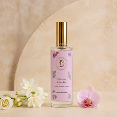 Illume - Room Freshener - 100 ML, Tuberose & Orchid spray bottle with gold cap beside white flowers and orchid