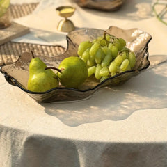Tableware glass bowl in dusk brown color with pears and grapes on a textured surface