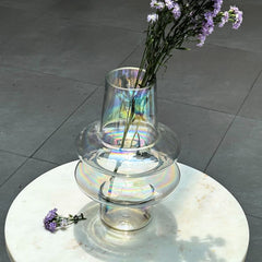 Iridescent glass vase with flowers on a marble surface