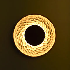 Round Terra Disc Wall Light with textured surface and central dark circle, casting warm light