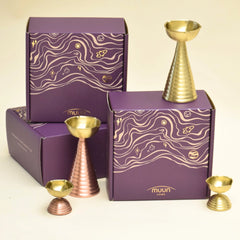 Brass Diya Pair Gift Set in brass and copper placed by a gift box by Muun Home
