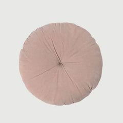 A round, dusty pink cushion with a central button and radiating stitched lines, shown from a top-down view on a light gray background.
