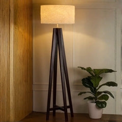 Hercules Phoenix Floor Lamp with a wooden base and beige shade in a room setting with a plant.