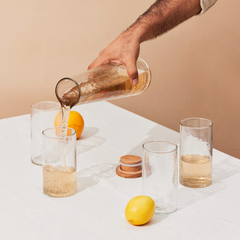 4 Hammered Glasses with textured design and Carafe filling water with lid placed on the table