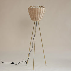 Wicker floor lamp with tripod base on a plain background