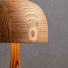 Close view of Belly table lamp with a whimsical, mushroom-like shape with a light fixture on the top made from sustainable waste plywood.