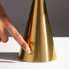 Portable chrome table lamp, cone-shaped base with 'fig living' branding, being touched by a hand on a neutral background