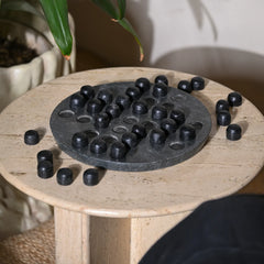 Black stone puzzle on a marble side table with plants in the background