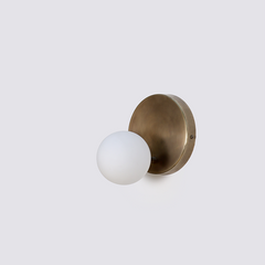 Designer Stem wall sconce with a glass globe attached to a metal brass stem