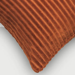 A close-up of a Luna Burnt Orange Velvet Cushion Cover showing its ribbed texture and corner against a light gray background.