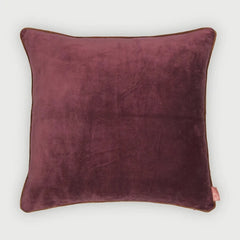 A square plum velvet throw pillow with piped edges, shown against a light gray background.