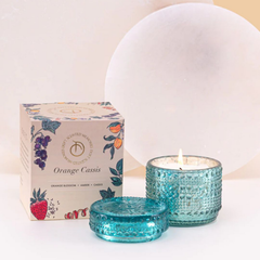Orange Cassis Fragrance Trinket Jar Candle, lit aqua glass jar with lid and box against a pale stone disc