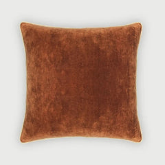A square throw pillow in a warm rust-brown velvet fabric, shown against a light gray background.