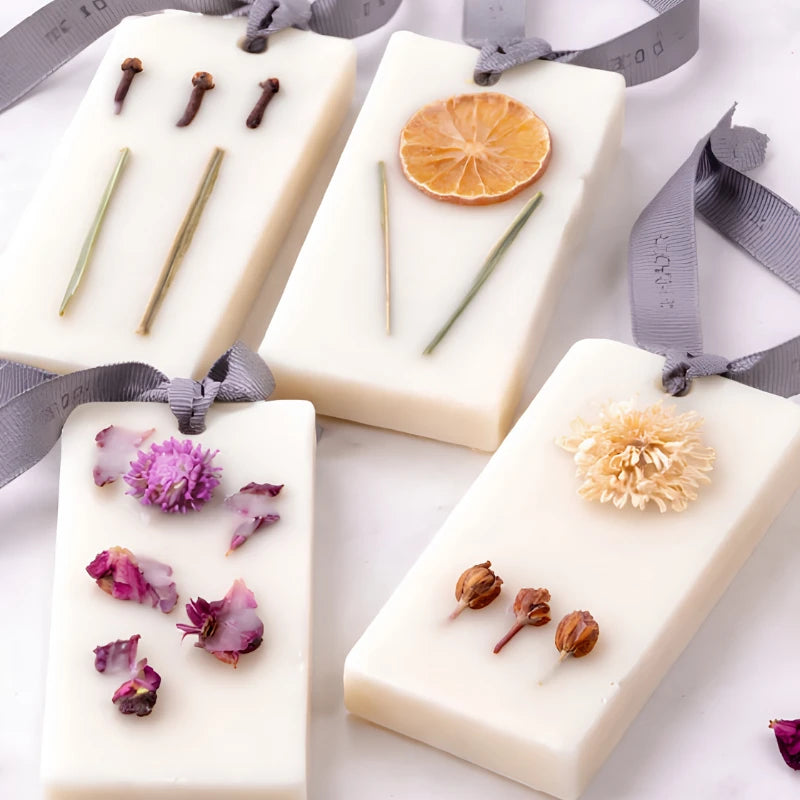 Flower Blossom & Lemongrass · Wax Tablet · Set of 4, four beeswax tablets with dried flowers and cloves on grey ribbons, top view
