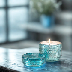 Orange Cassis Fragrance Trinket Jar Candle, lit aqua glass jar with lid on a reflective tabletop