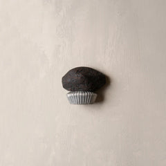 Small dark stone with a silver base on a beige background