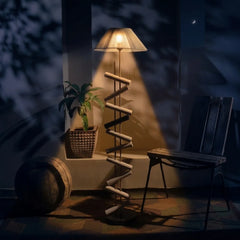 Dark room with a lamp casting light on a plant and chair.