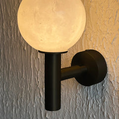 Close-up of alabaster wall lamp showing stone texture and veining with black metal base