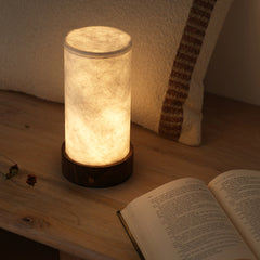 Decorative magnus table lamp with banana paper shade and a wooden base, illuminated glow light.