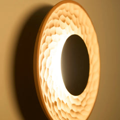 Close-up of a circular Terra Disc Wall Light fixture with a textured surface and black metallic center