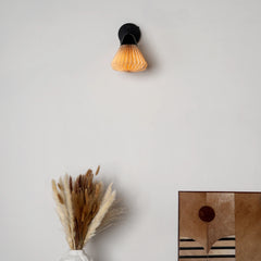 Wall-mounted Linen Downlighter Wall Sconce with a decorative glowing bulb on a plain wall.