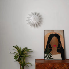 Daisy Wall light in layered petals unique design looks like a geometric wall sculpture on a light gray wall.