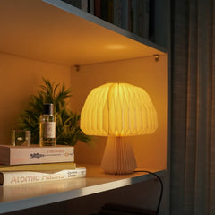 Mushroom Origami Table Lamp with warm glow light next to room spray bottle and books