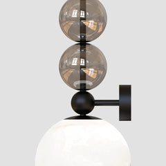 Modern wall-mounted light fixture with glass shades & warm light spilling across the alabaster grain