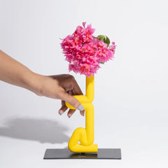 Yellow abstract vase with pink flowers against a white background