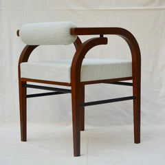 A wooden dining chair with a curved reddish-brown frame, a cylindrical back cushion, and a square seat cushion upholstered in a light beige textured fabric, set against a white fabric backdrop.