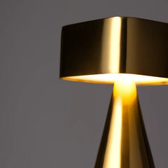 Gold chrome table lamp, cone-shaped base casting warm light
