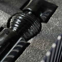 A close-up of a glossy black glass Carafe nestled in textured gray foam packaging.