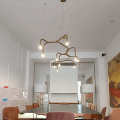 Branch light by hatsu , in a living room setting, consisting of multiple curved rods arranged in a asymmetric pattern, with lighting fixtures at the ends.