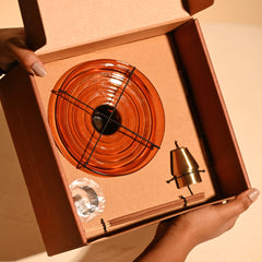 Decorative amber color glass disc with brass Incense Holder inside an open gift box.