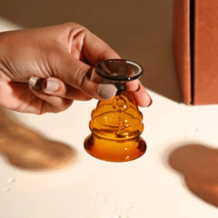 Kalash Oil Lamp + Small Ringing Bell, hand holding amber glass bell with dark rim, close-up