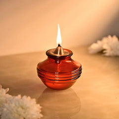 Kalash Oil Lamp, lit amber borosilicate glass kalash lamp with gold-tone cap, close-up