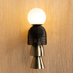 Totem Black Wall Lamp with a black woven basket and gold design on a beige wall