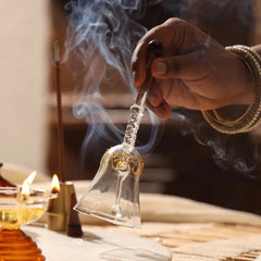 Kalash Oil Lamp + Ringing Bell, hand ringing twisted-stem glass bell amid incense smoke