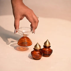 Muun Diya Gift Box, hand placing short diya beside two mini kalash with brass caps