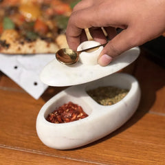 Twin Marble Server, hand lifting lid with gold spoon to reveal two spice compartments