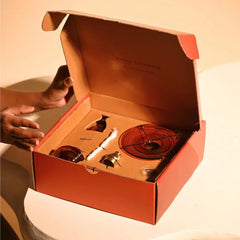 Kalash Oil Lamp + Incense Holder + Small Bell, hands opening orange gift box to reveal set inside