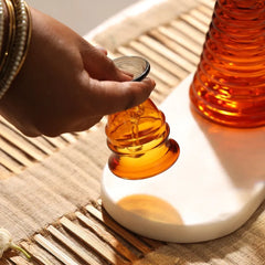 Glass Short Ringing Bell, hand holding amber short glass bell on white tray