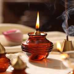 Kalash Oil Lamp, lit amber glass kalash lamp with incense burning behind, altar setting