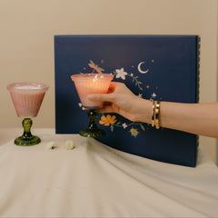 A set of two ribbed glass votive candles with dark green stems, beautifully presented in a navy blue decorated gift box.