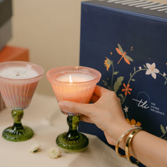 A set of two ribbed glass votive candles with dark green stems, beautifully presented in a navy decorative gift box branded with "the living influence" in the background.