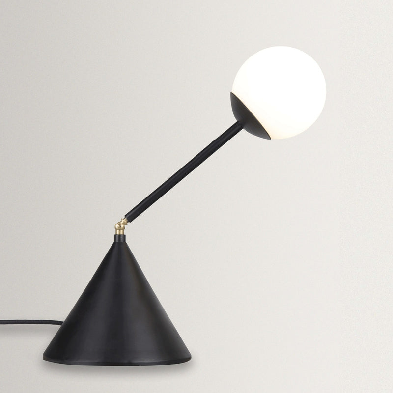 Black adjustable desk lamp with white bulb on a light gray background
