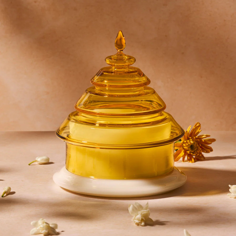 Decorative yellow glass candle with a white base on a beige background
