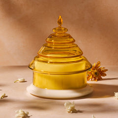 Decorative yellow glass candle with a white base on a beige background