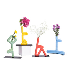 Colorful abstract Vrikhasana Ceramic Vase sculptures with flowers on a white background
