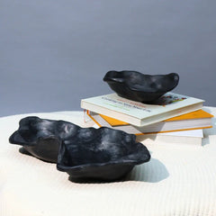 Two black ceramic organic bowls with a swirled edge design, displayed on a white textured surface.
